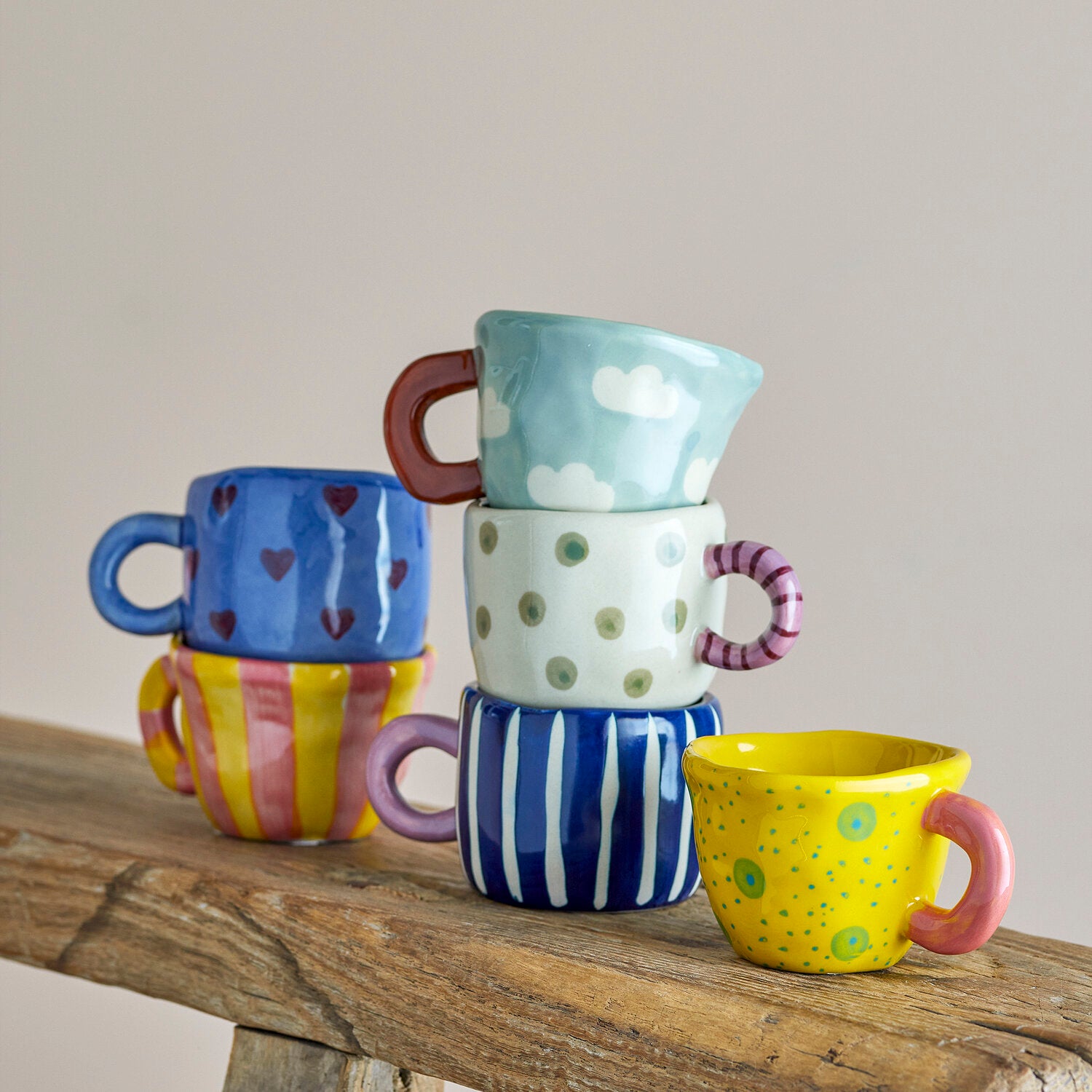 Blaue Tasse mit Wolkenmuster und rotem Henkel auf Holzplatte