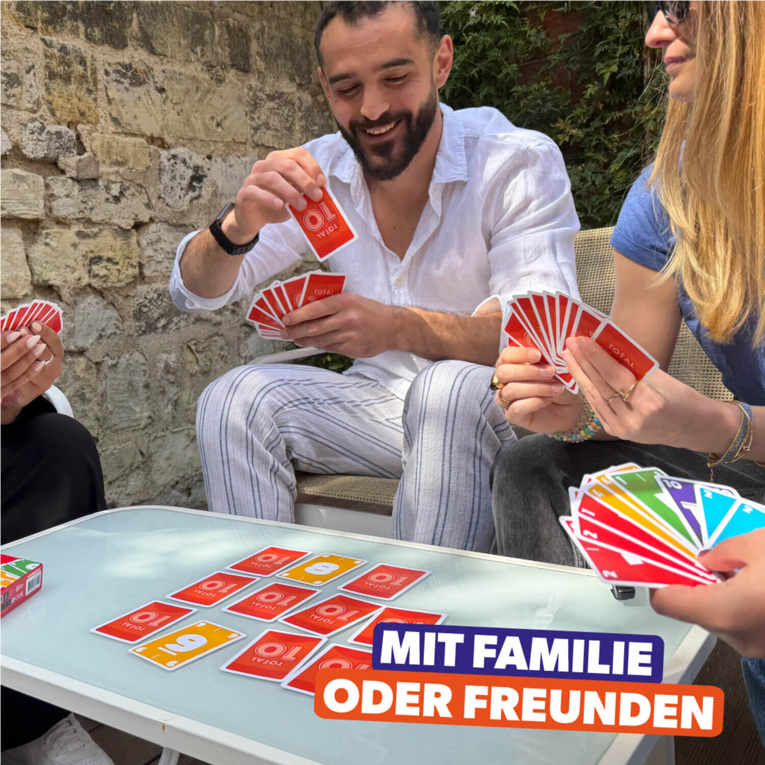 Gesellschaftsspiel Total 10: Spieler halten Karten, Kartenreihe und Schachteln auf Tisch