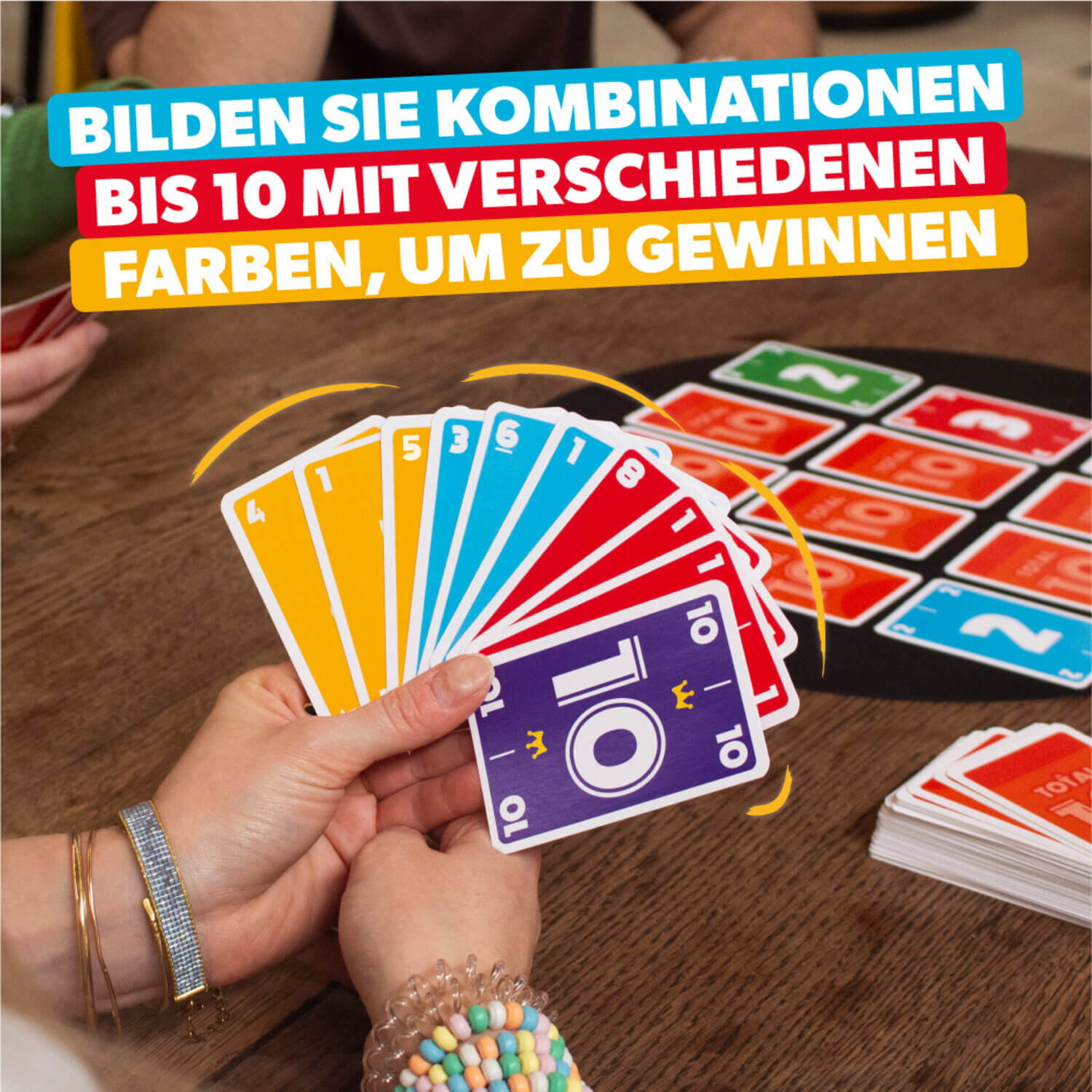 Spielkarten Total 10 in der Hand, bunte Nummern-Karten auf Holzoberfläche