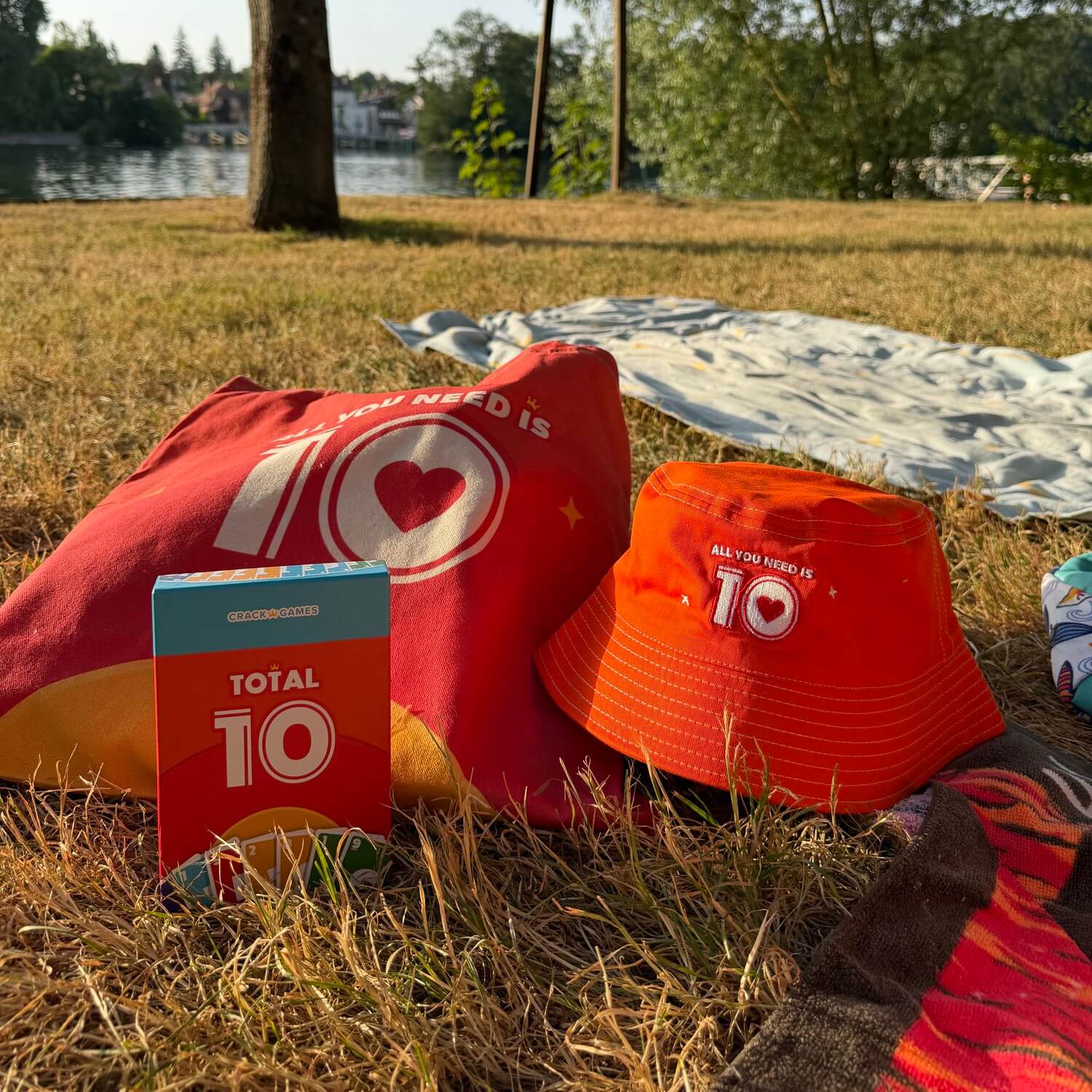 Outdoor-Set Total 10: rote Schachtel, roter Hut und Tuchbeutel auf Decke im Gras