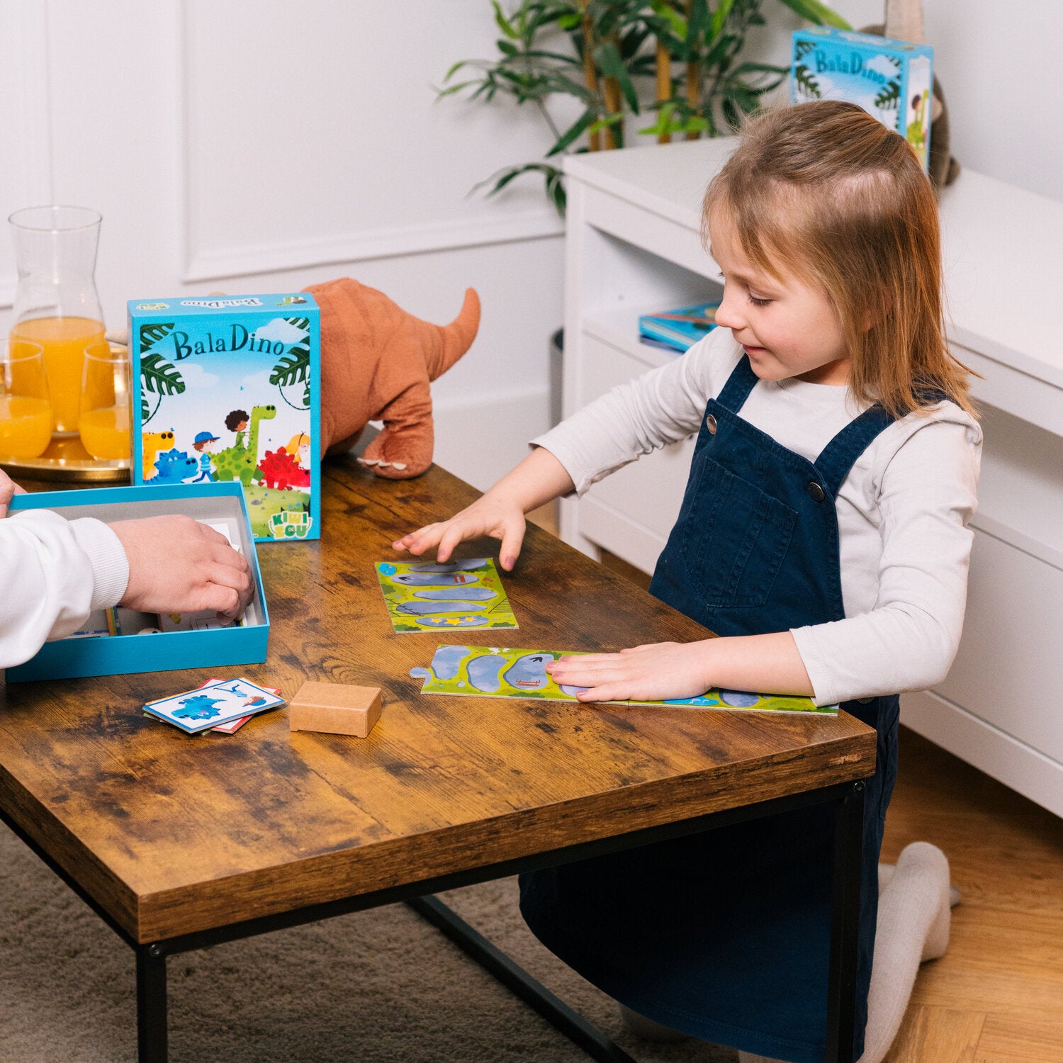 Dino-Brettspiel: Kind spielt mit Figuren und Karten vor Box und Spielmatte