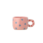 Rosa Tasse mit blau gepunktetem Muster und rot-weißem Henkel.