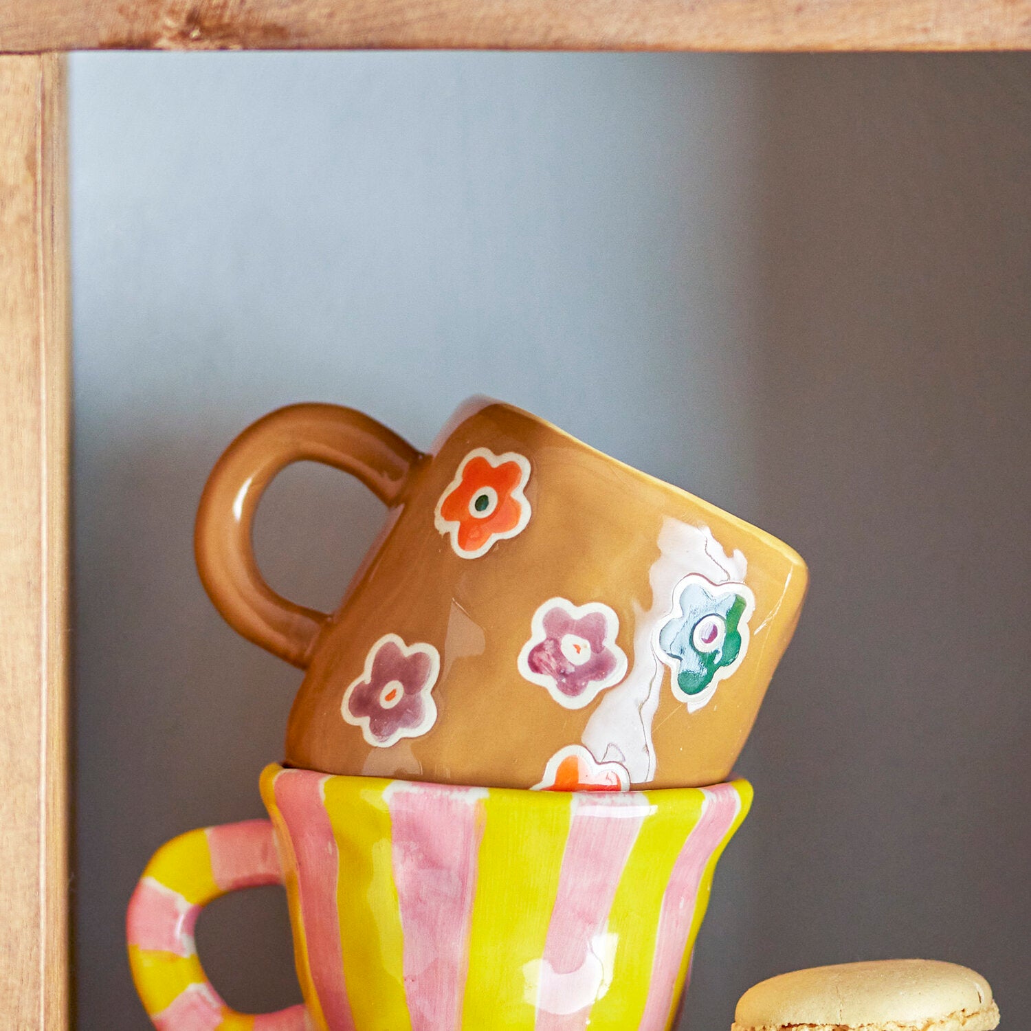 Orangefarbene Tasse mit Blumenmotiven und breitem gestreiftem Rand, seitlicher Henkel.