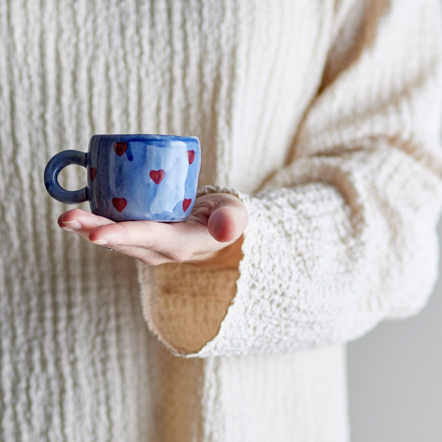Blaue Herz-Tasse in der Hand gehalten, mit seitlichem Henkel