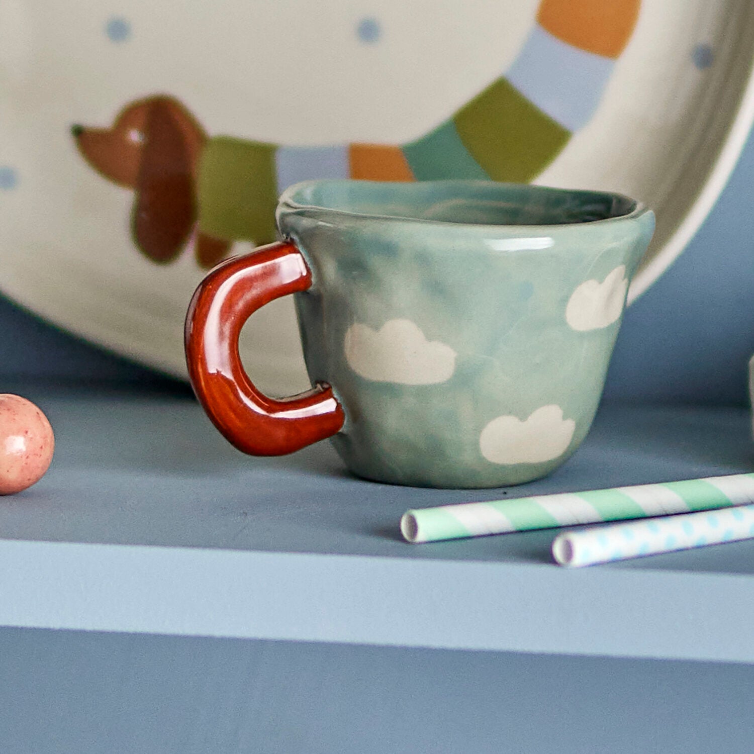 Nahaufnahme: blaue Tasse mit Wolkenmuster und rotem Henkel