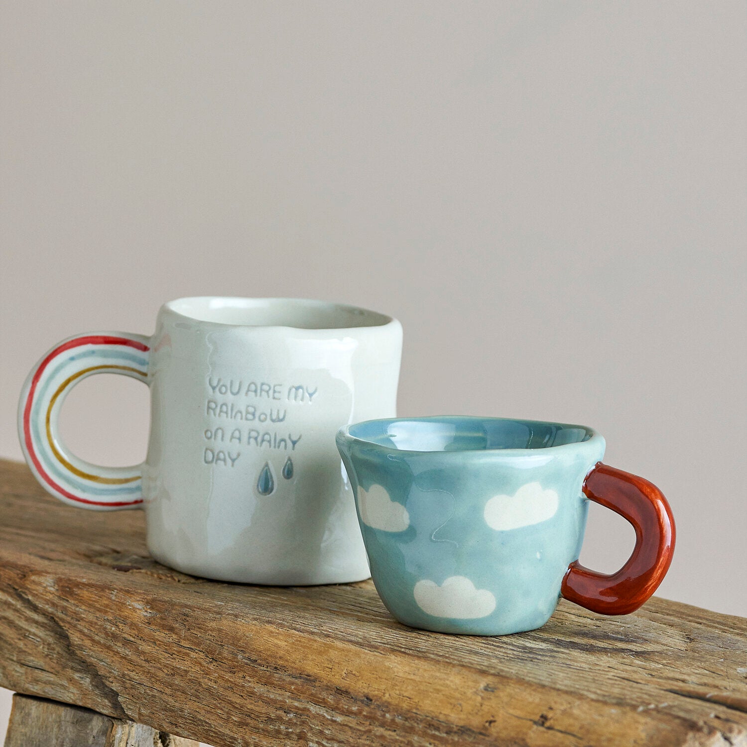 Blaue Tasse mit Wolkenmuster und rotem Henkel, neben weißer Tasse