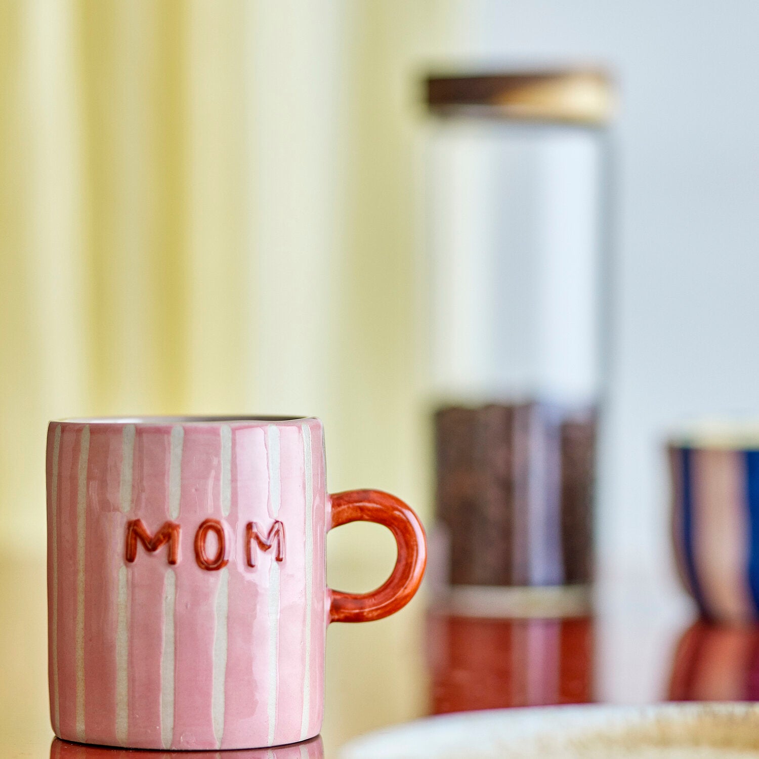 Rosa Keramikbecher mit weißen Streifen und Aufschrift „MOM“, brauner Henkel
