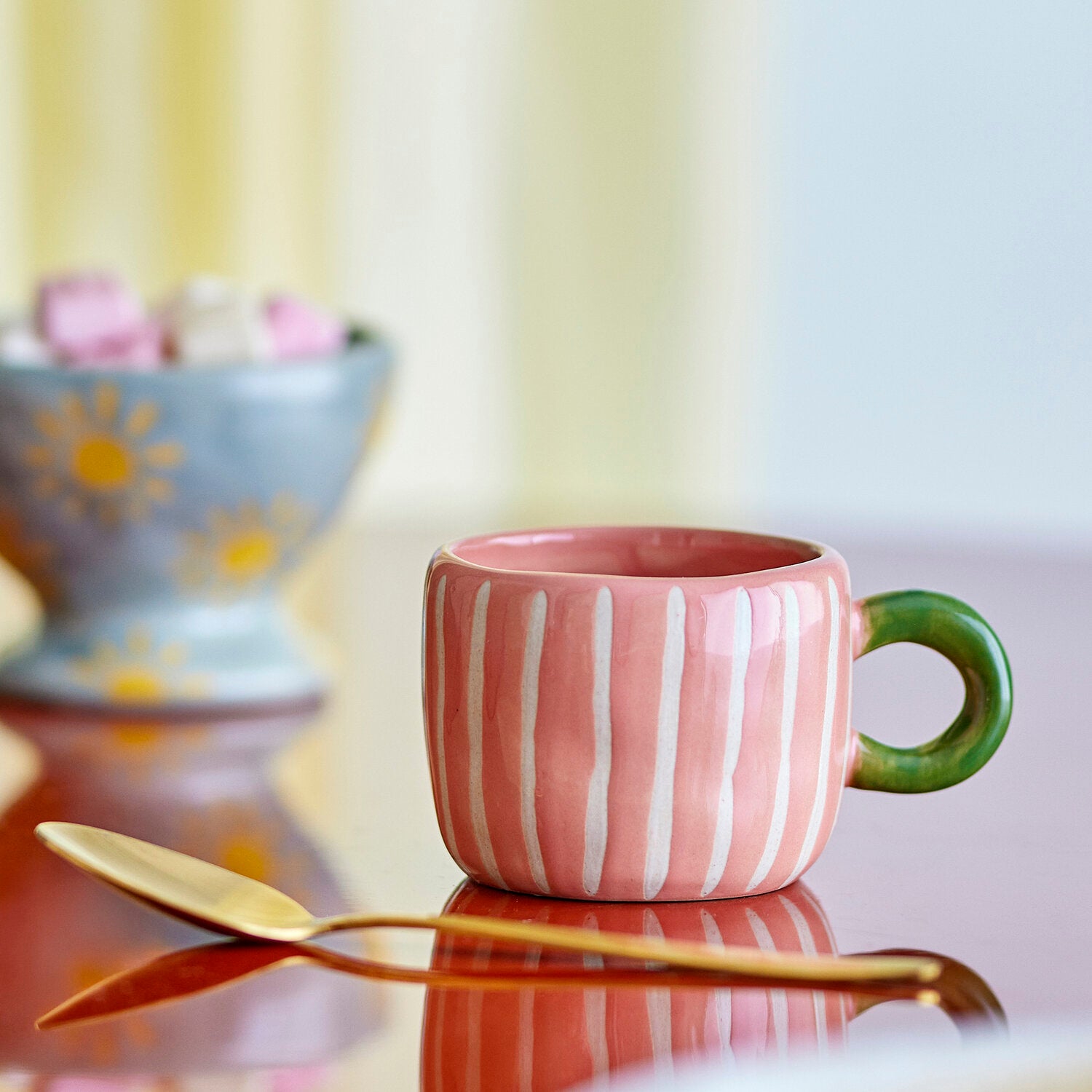 Rosa Keramik-Tasse mit weißen Streifen und grünem Henkel, seitliche Ansicht