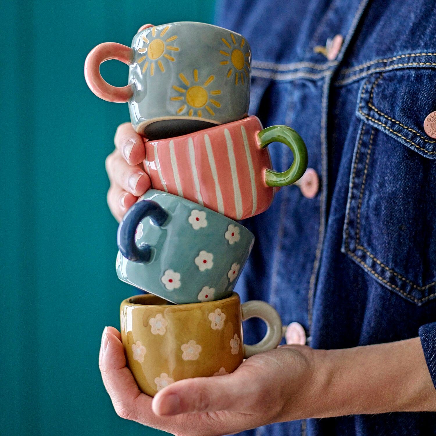 Rosa Tasse mit weißen Streifen und grünem Henkel, von Hand gehalten