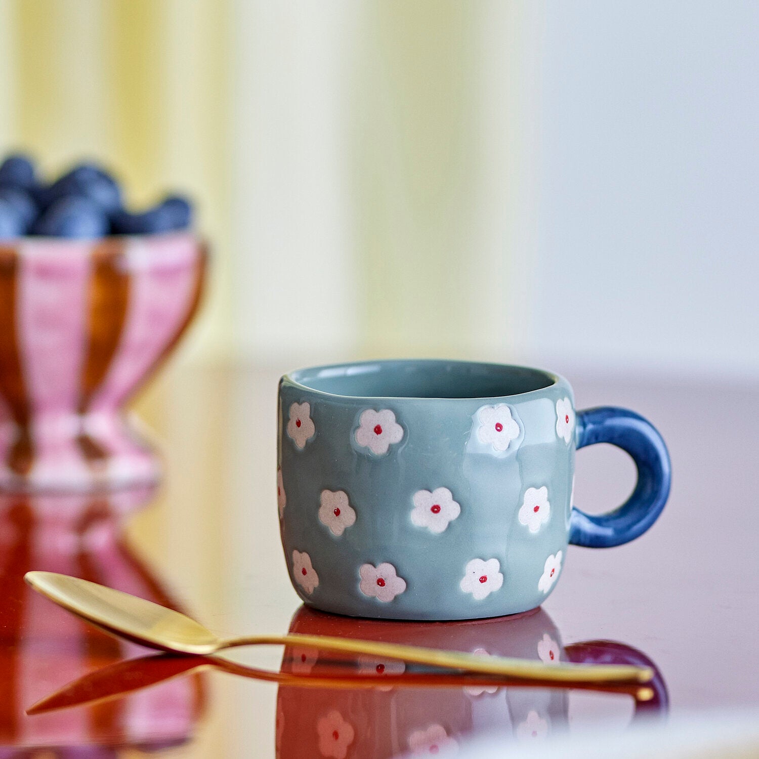 Türkisfarbene Keramiktasse mit Henkel und weißen Blüten, kleine Farbakzente
