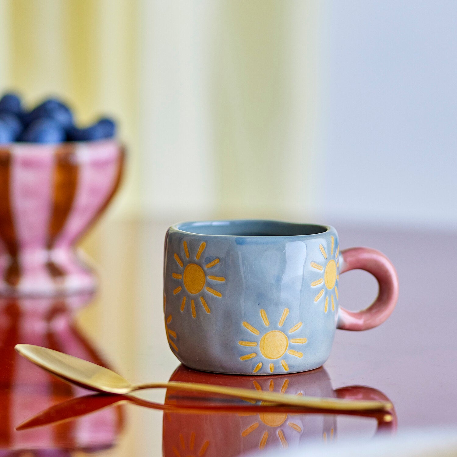 Hellblaue Tasse mit Sonnenmotiv und rosafarbenem Henkel