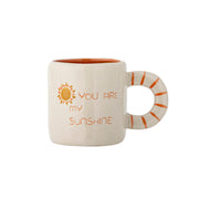 Weiße Tasse mit orangefarbenem Rand und Aufdruck „YOU ARE MY SUNSHINE“