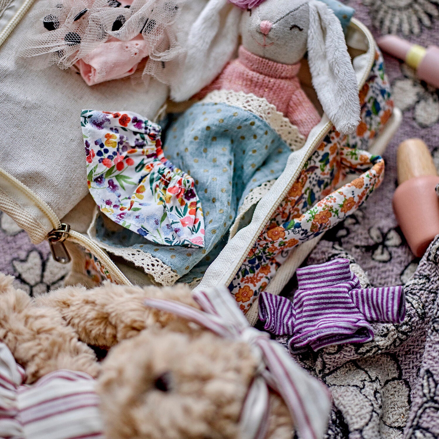 Offenes Reiseetui mit Stoffpuppe, Tüll, rosafarbenem Strickteil und gestreiftem Kleidchen