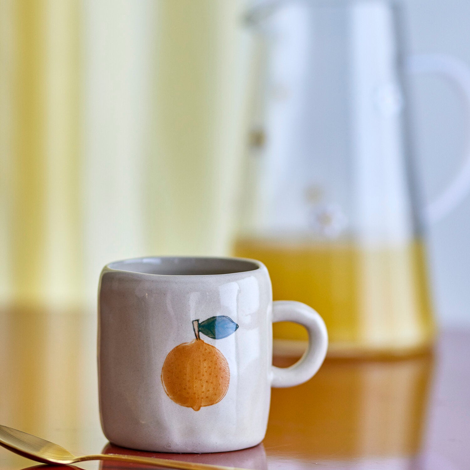 Cremefarbene Keramiktasse mit Orange-und-Blatt-Motiv, Henkel zur Seite