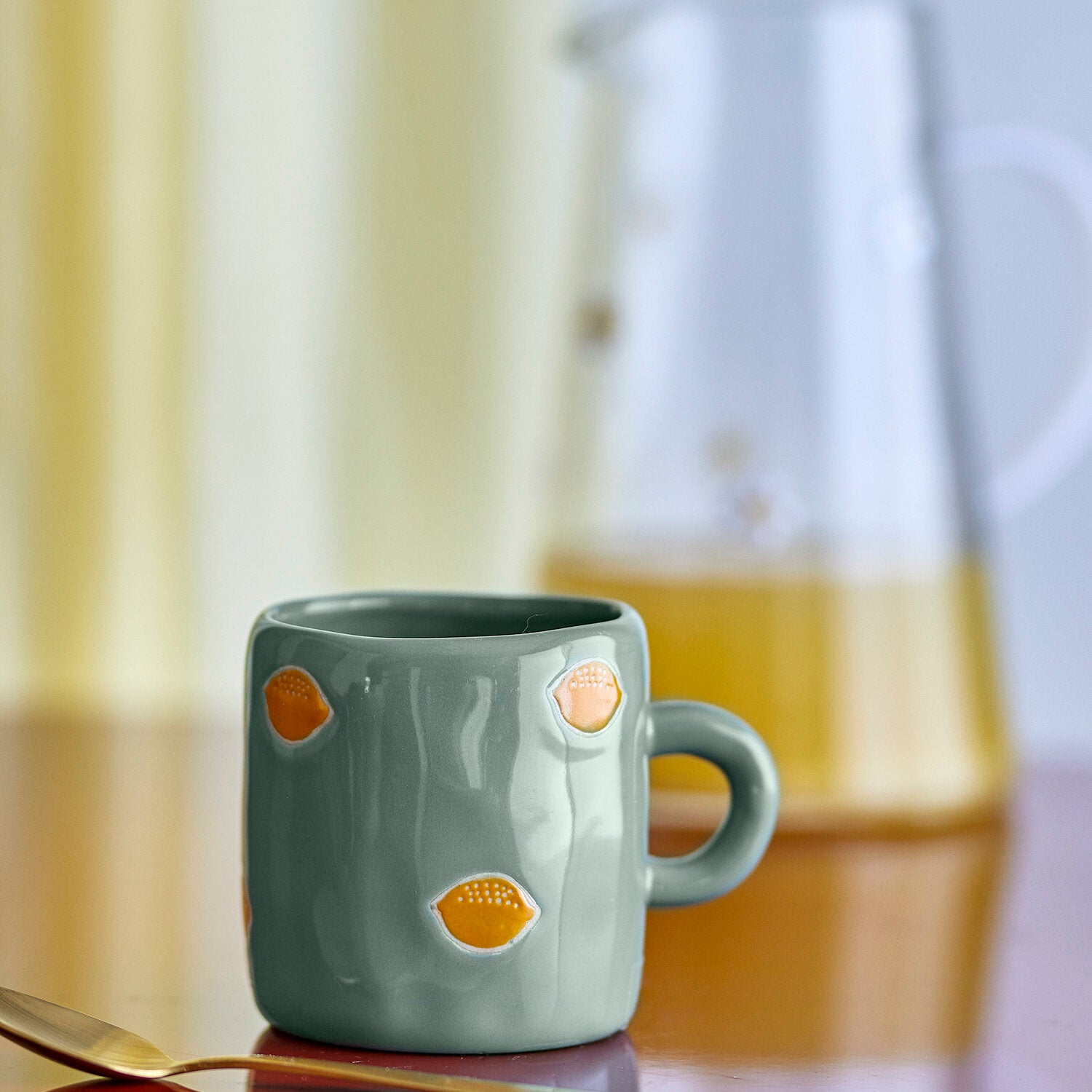 Kleine Keramik-Tasse in Petrolgrün mit orangefarbenen Orangen-Motiven und Henkel