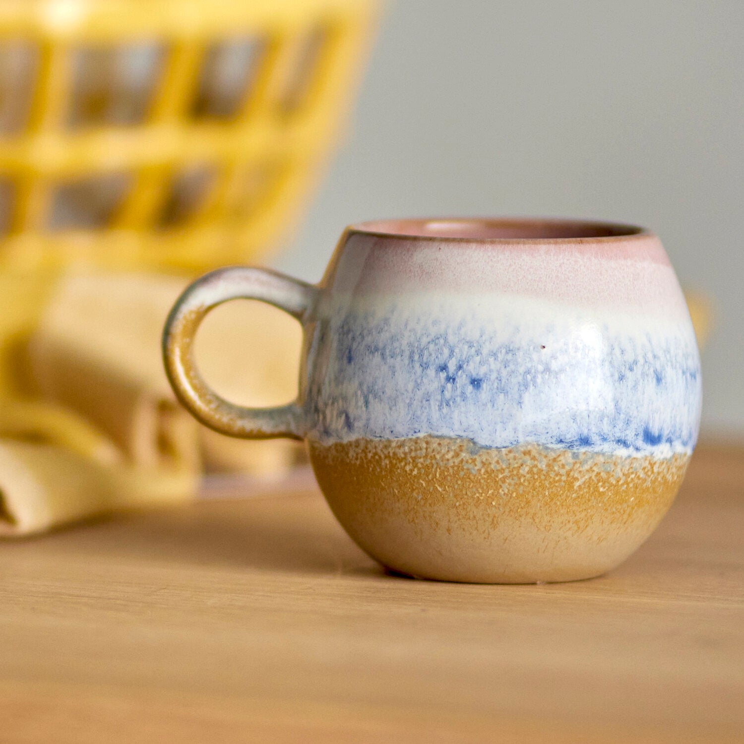 Keramikbecher mit Henkel, rosa-violetter Rand, blauer Streifen und goldbraune Unterkante