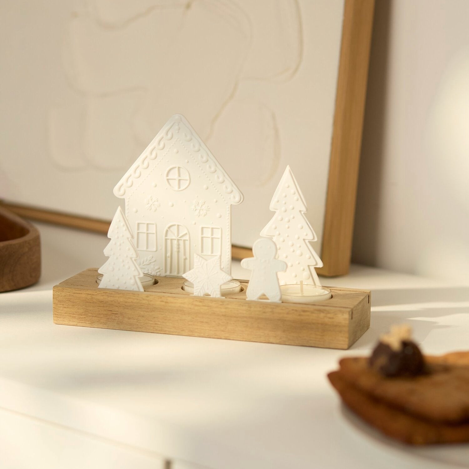 Lichtszene mit weißem Haus und Figuren auf Holztablett, warmes Kerzenlicht