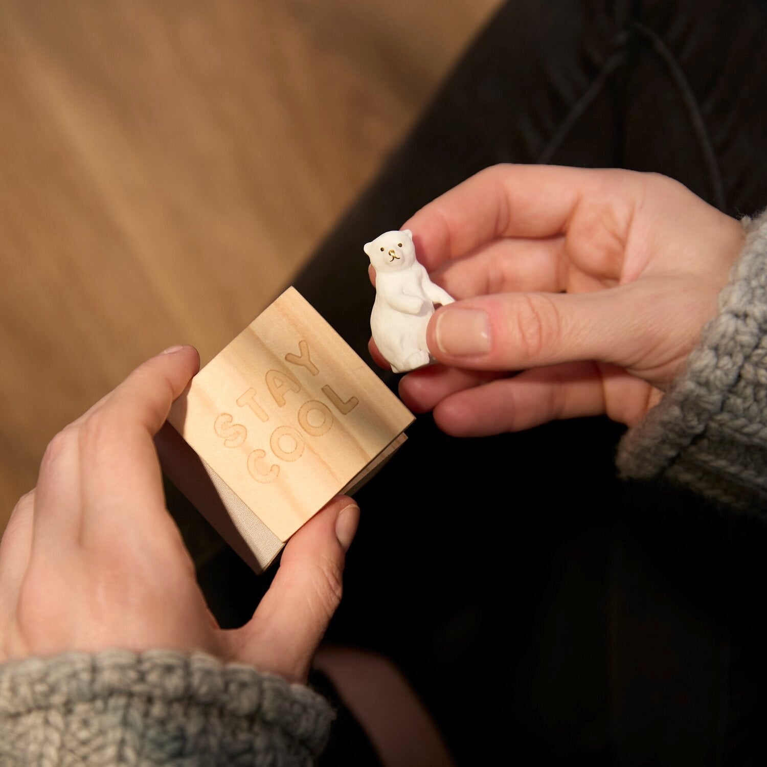 Hände halten kleines Holz-Glückskästchen mit Eisbärfigur auf dem Deckel