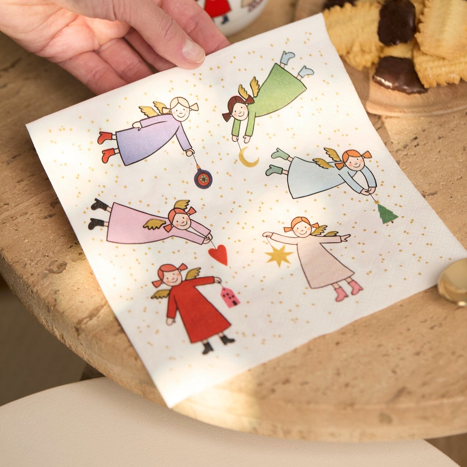 Papierserviette, von Hand gehalten, mit Engel-Motiven und goldenen Punkten