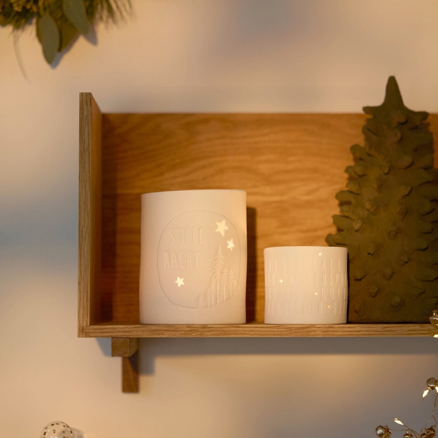 Zwei weiße Teelichter in einem Holzregal
