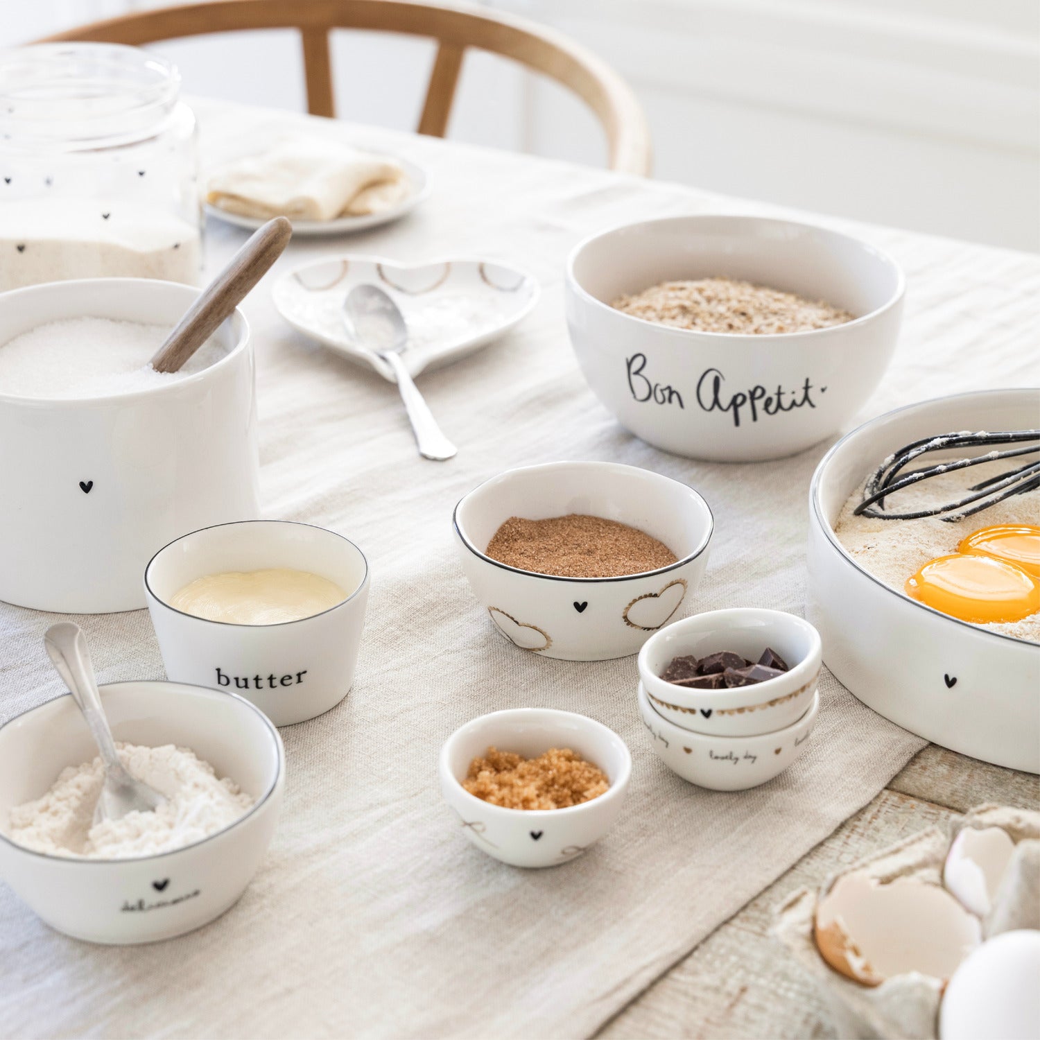 Weiße Kaffeetassen mit schwarzem Herzmotiv auf gedecktem Tisch, Keramik