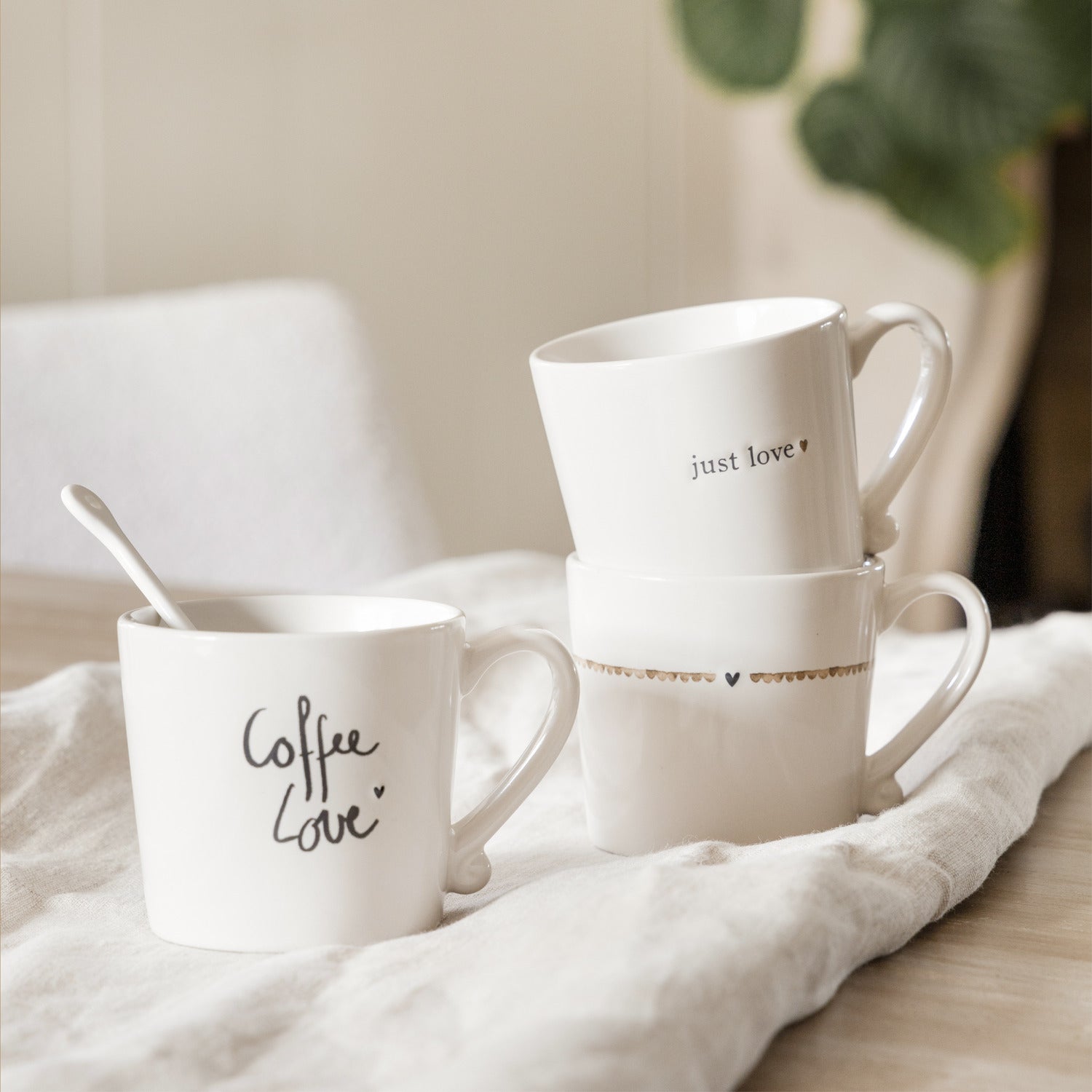 Weiße Tassen auf Stoffunterlage, eine mit „Coffee Love“, eine mit „just love“