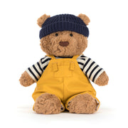 Brauner Kuschelbär mit dunkelblauer Mütze und gelbem Seefahrer-Latzanzug, gestreiftem Shirt