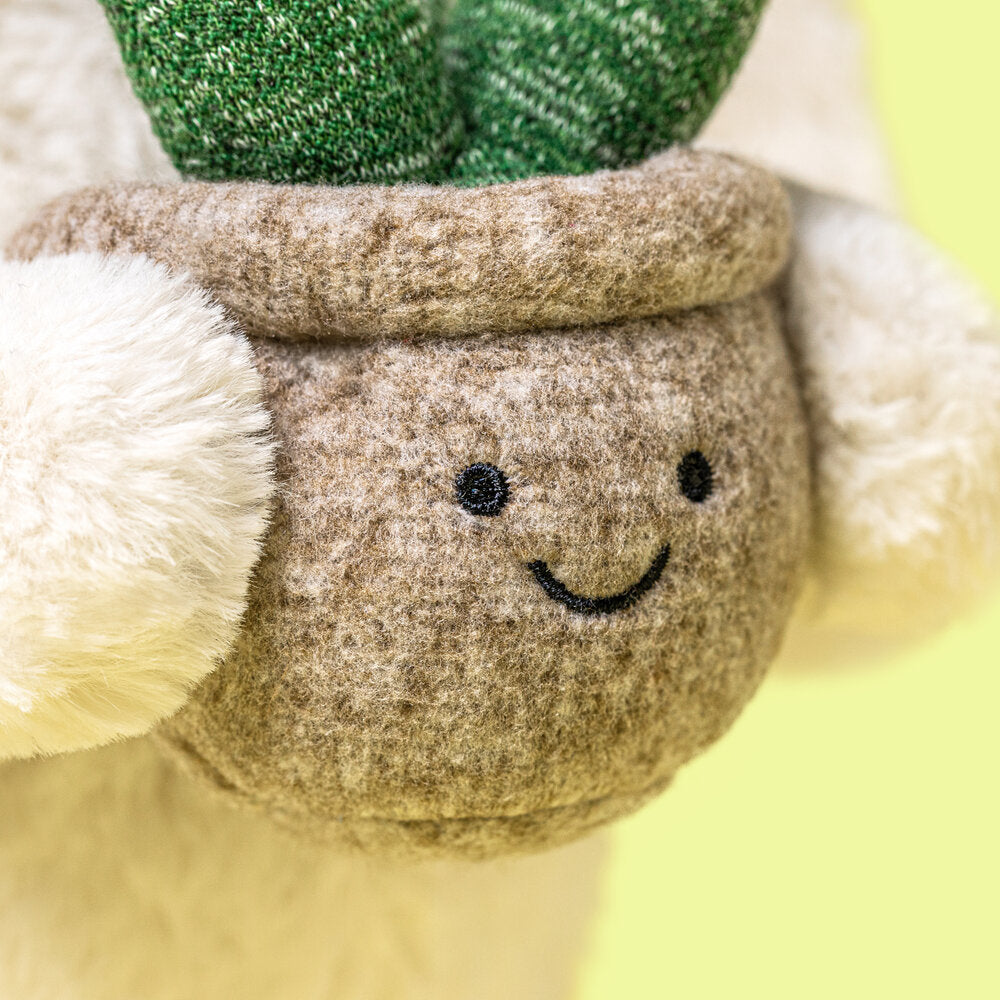 Kuscheltierhase-Ansicht mit grauem Pflanzentopf, lächelnder Stickerei und grünen Blättern
