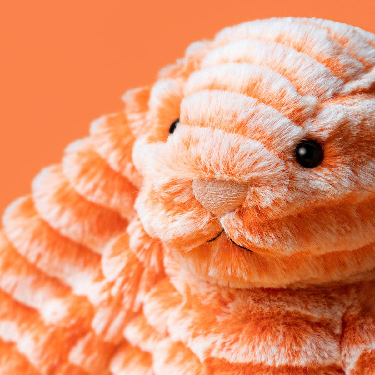 Nahaufnahme vom Gesicht eines orangefarbenen Kuscheltierhasen mit dunklen Knopfaugen.