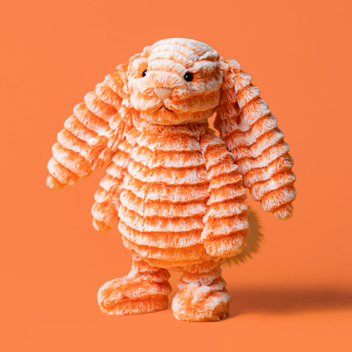 Kuscheltierhase aus orangefarbenem Plüsch, Ganzkörperansicht mit leicht gedrehter Pose.