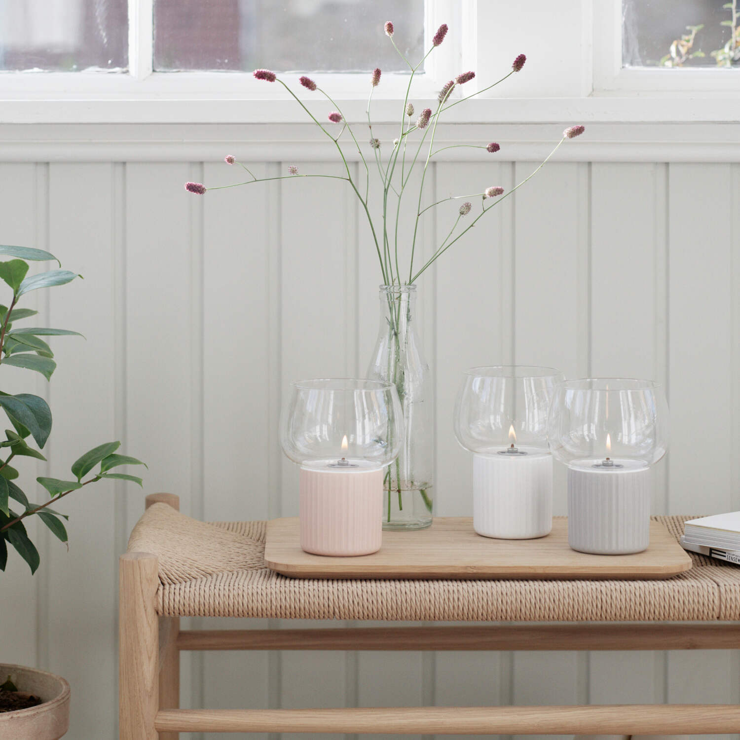 Windlicht HYGGE mit transparentem Glas und geriffeltem rosa Sockel, auf Holztablett