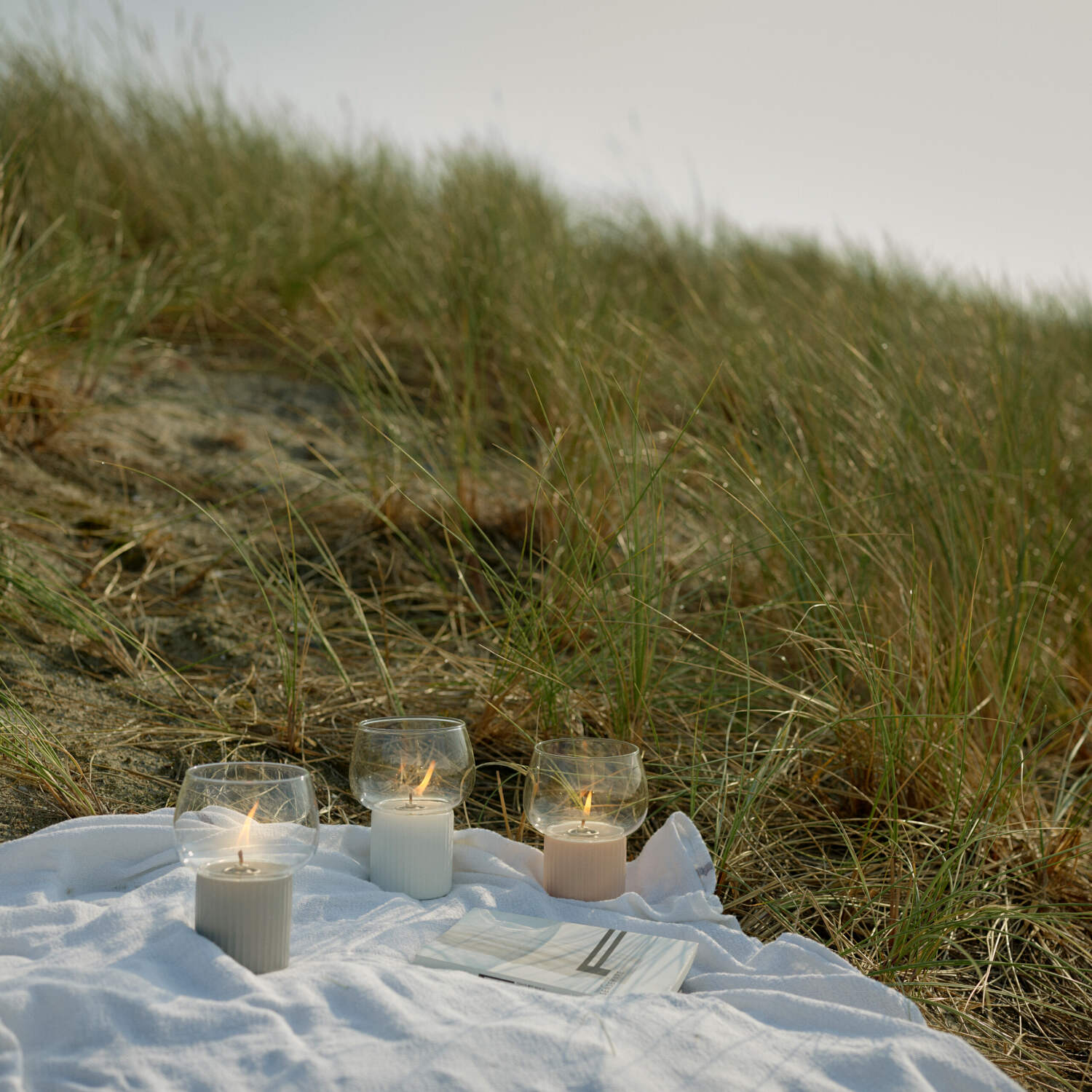 Windlicht HYGGE mit geriffeltem rosafarbenem Sockel und Glaszylinder im Freien