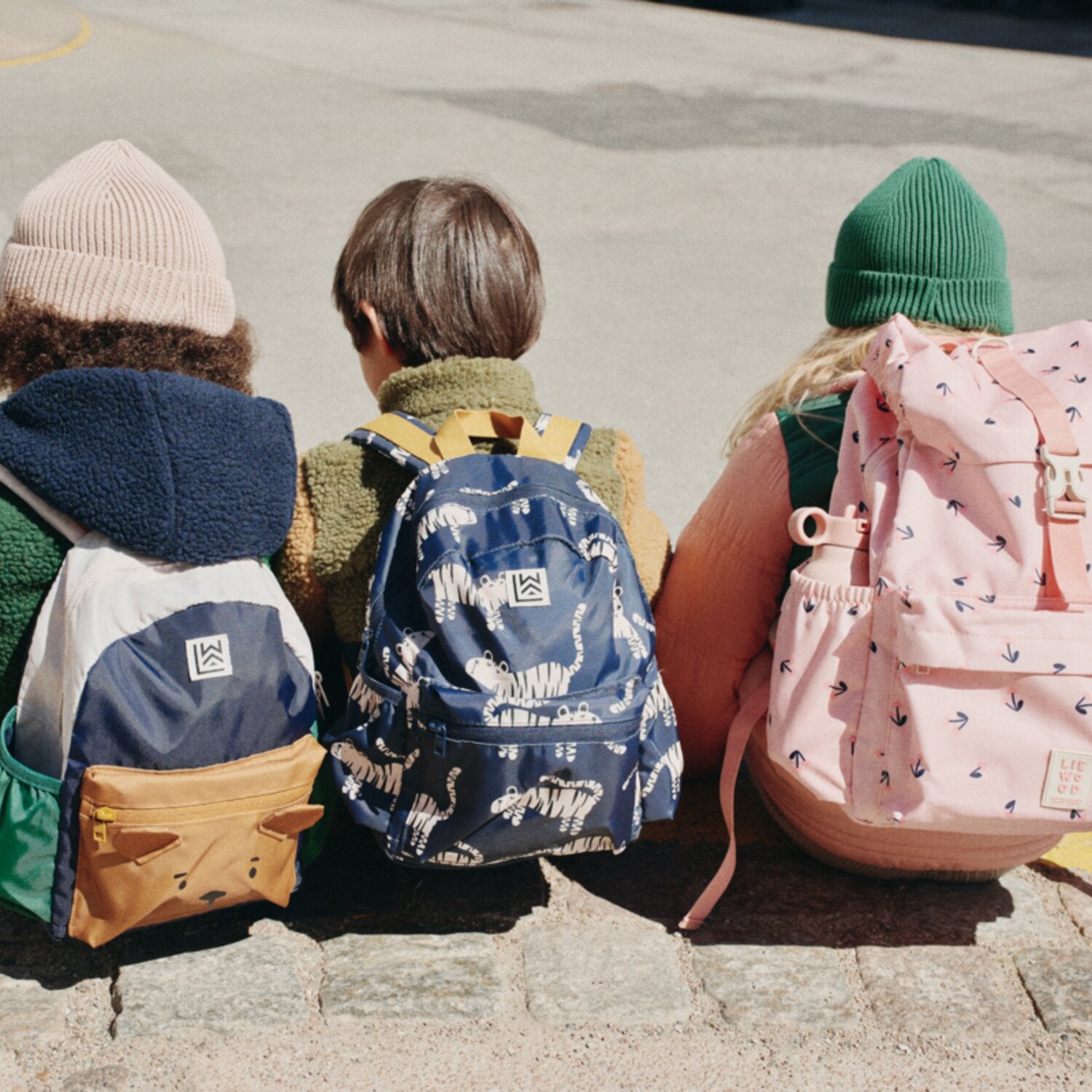 Kinder-Schulrucksäcke getragen: dunkelblau, gelb-bunt und rosafarben