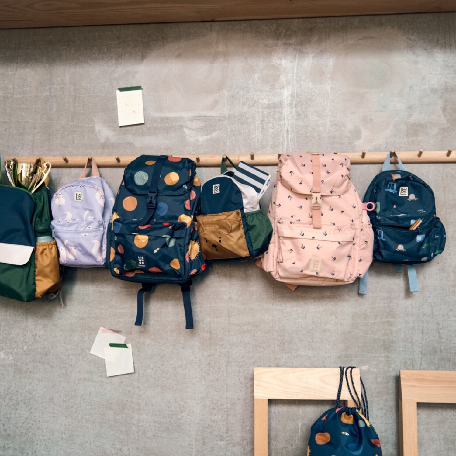 Mehrere Schulrucksäcke an Wandgarderobe, verschiedene Farben und Muster
