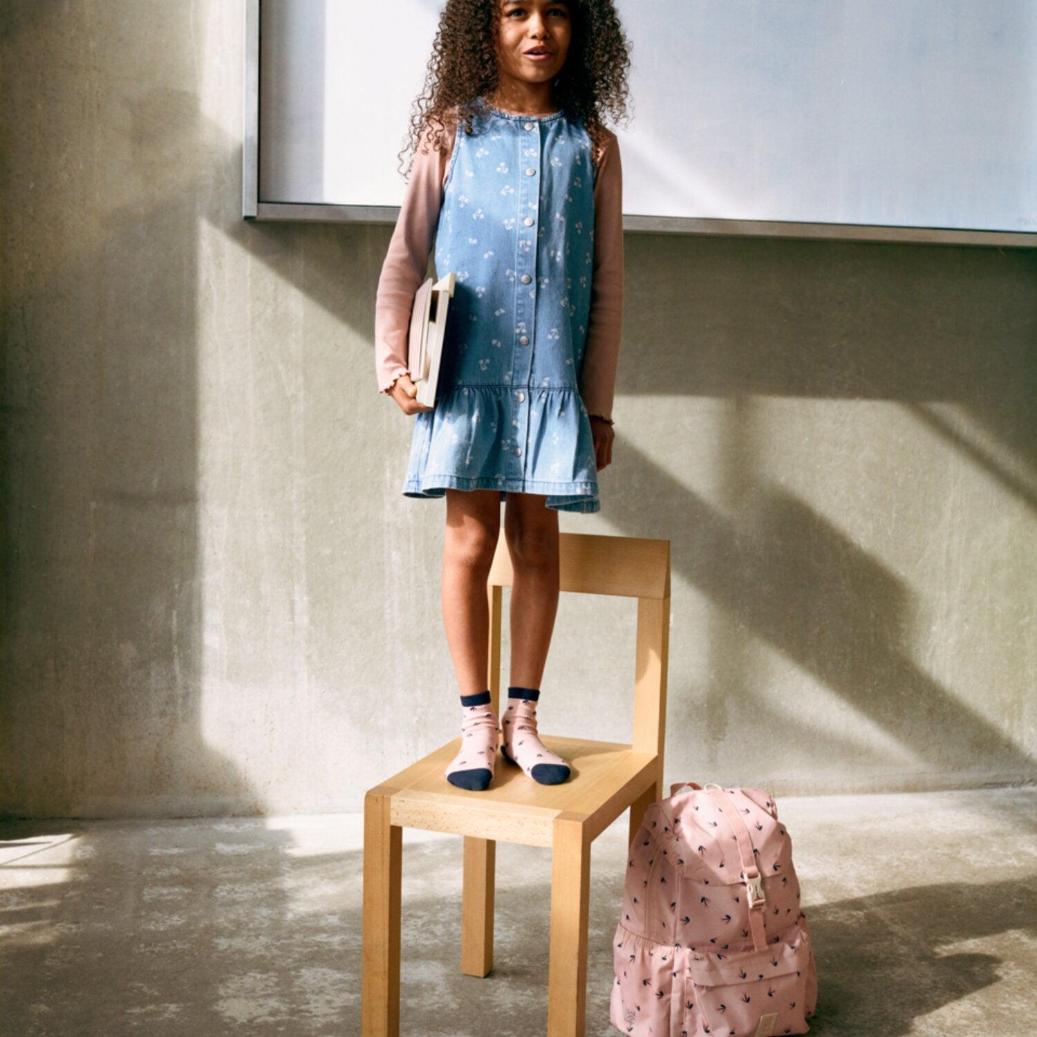 Rosa Schulrucksack mit Herzmuster, stehend neben dem Kind