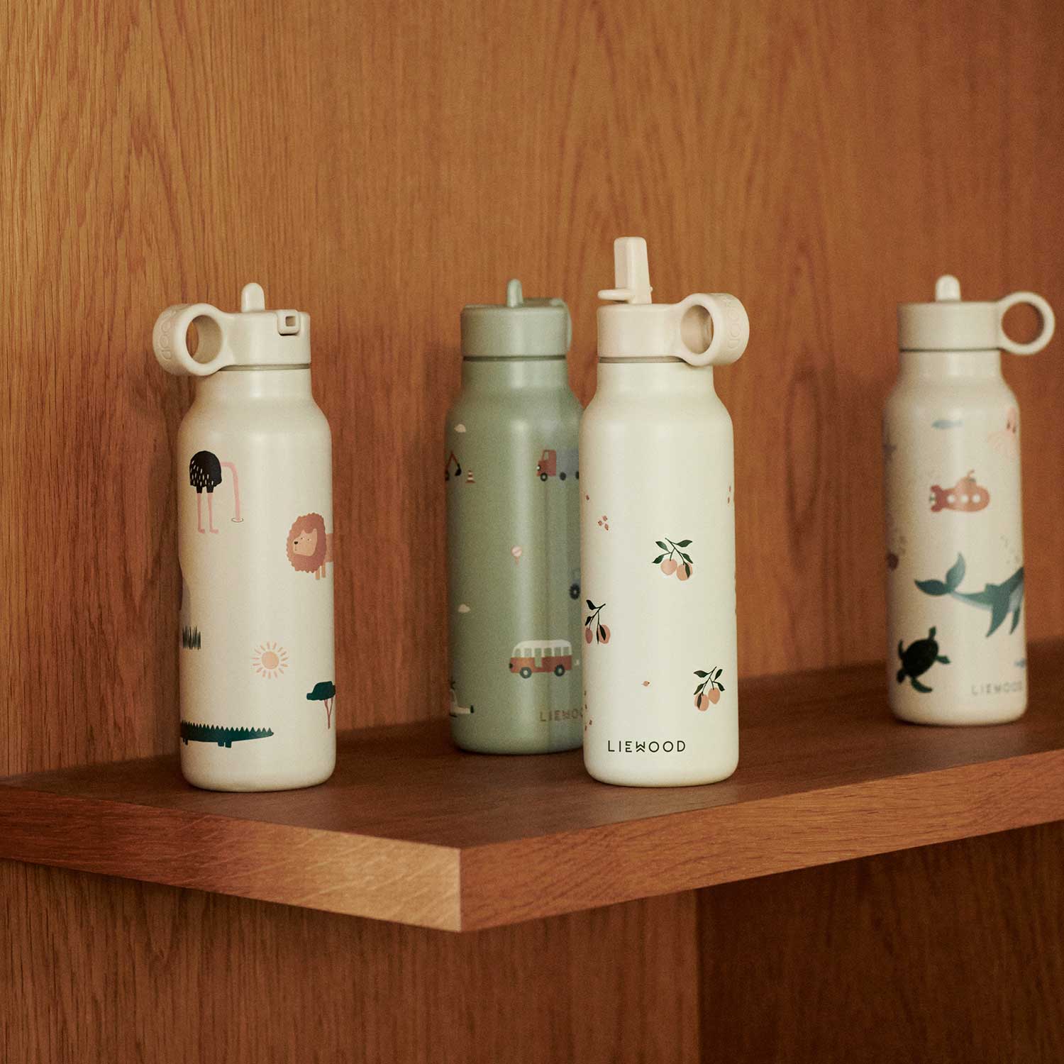 Drei Wasserflaschen mit Motivdesign in Pastellfarben auf Holzregal