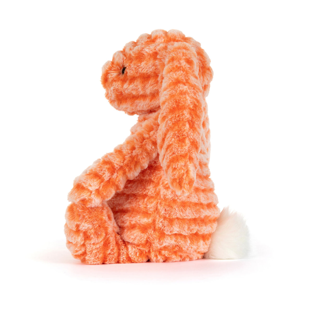 Kuscheltierhase aus orangefarbenem Plüsch, seitliche Ansicht im Sitzen.