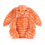 Kuscheltierhase aus orangefarbenem Plüsch, sitzt zusammengerollt.