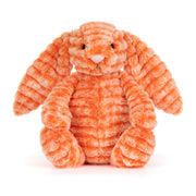 Kuscheltierhase aus orangefarbenem Plüsch, sitzt zusammengerollt.