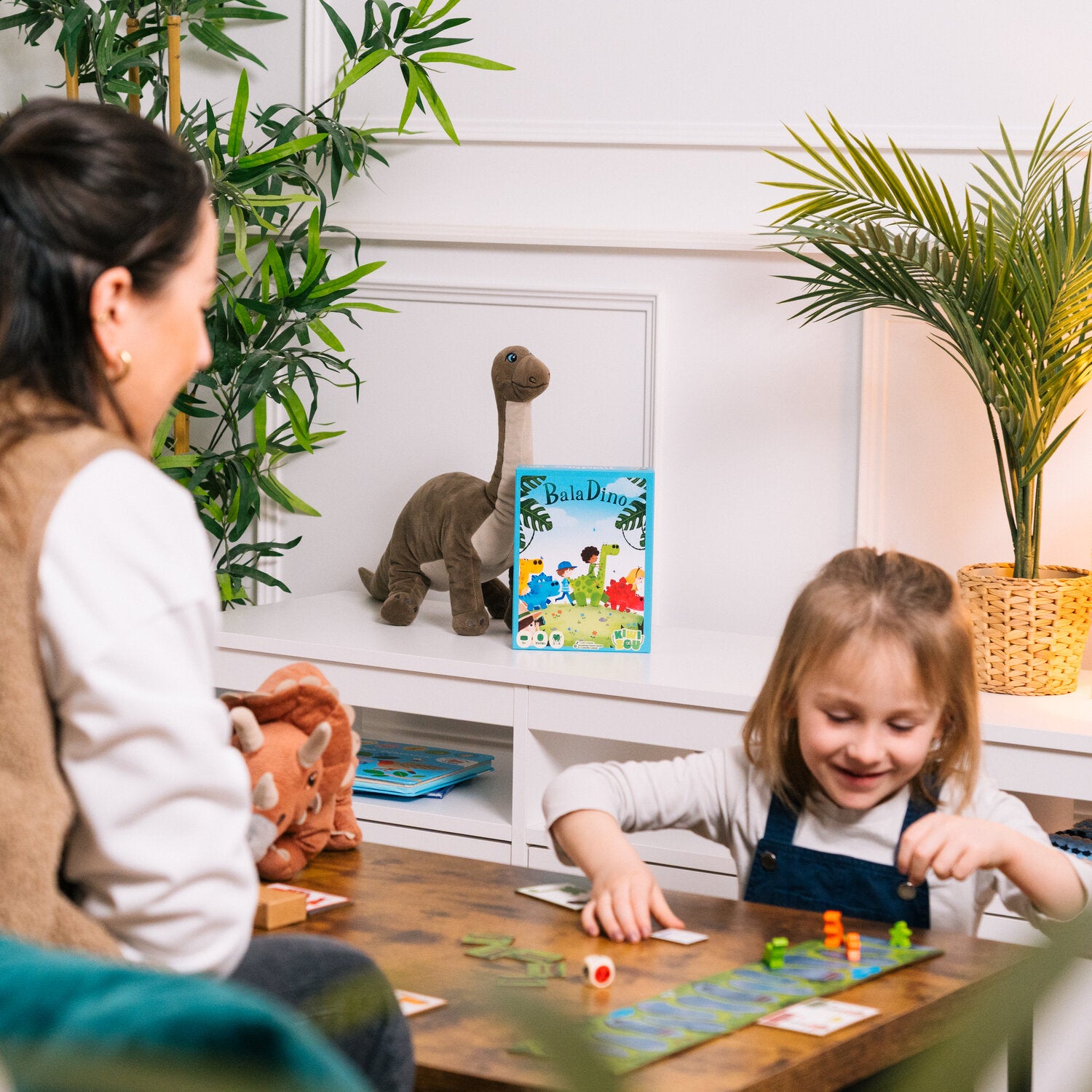 BalaDino Brettspiel: Kinderszene am Tisch mit Dino-Karten und Figuren
