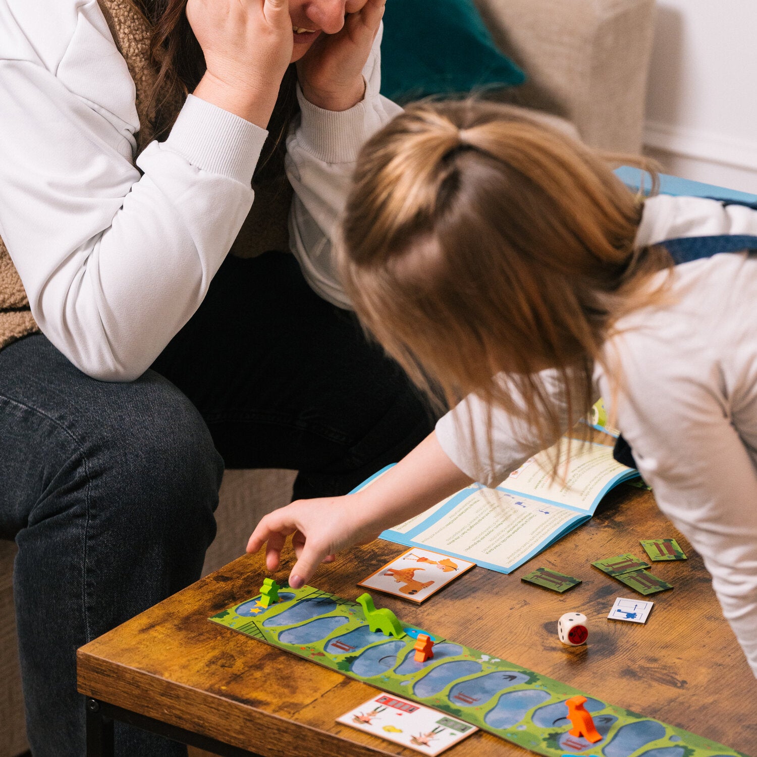 BalaDino Brettspiel am Tisch: Kinder schieben Karten und Figuren auf dem Spielfeld