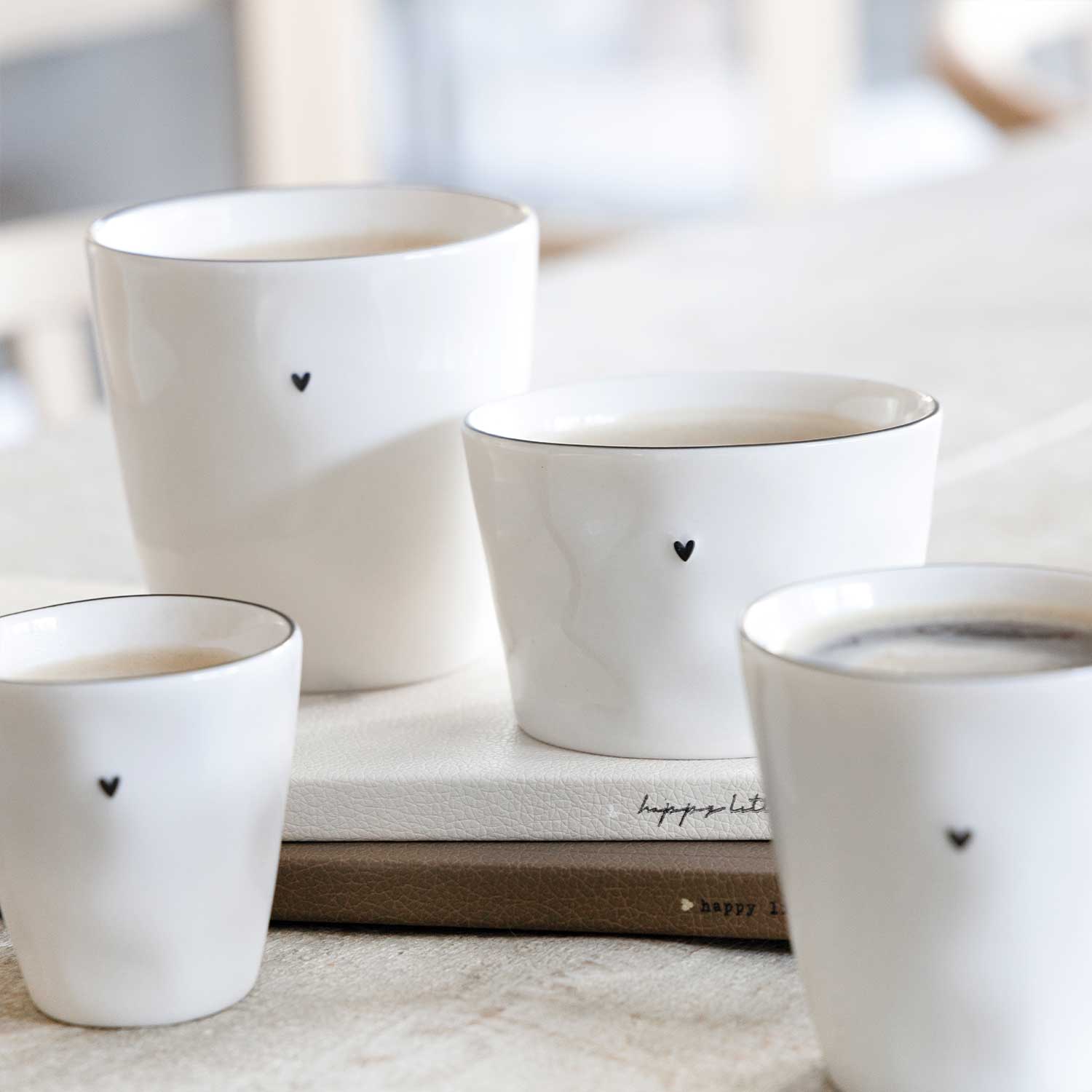 Mehrere weiße Kaffeetassen mit schwarzem Herz auf Vorderseite, Keramik