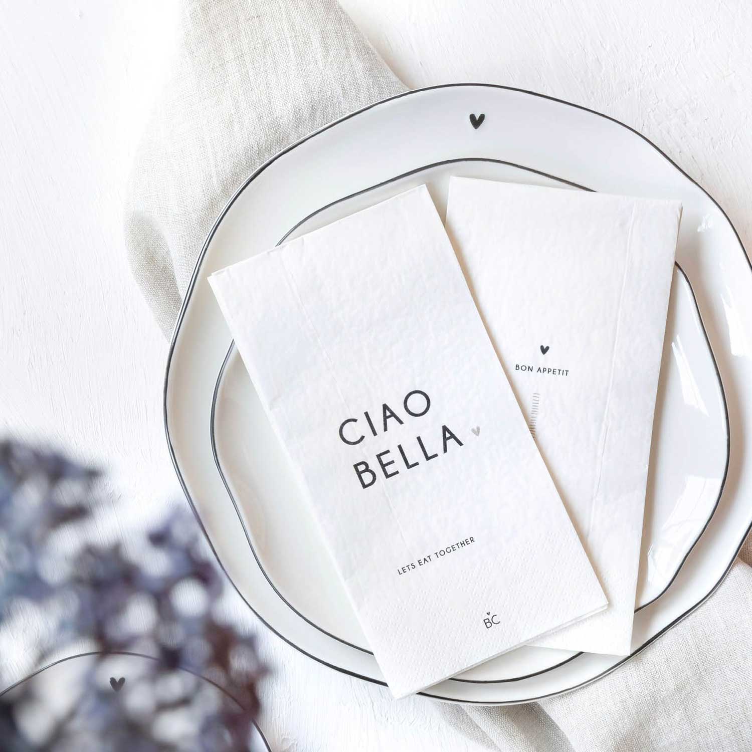Papierservietten weiß mit „CIAO BELLA“-Aufdruck, gefaltet im Teller