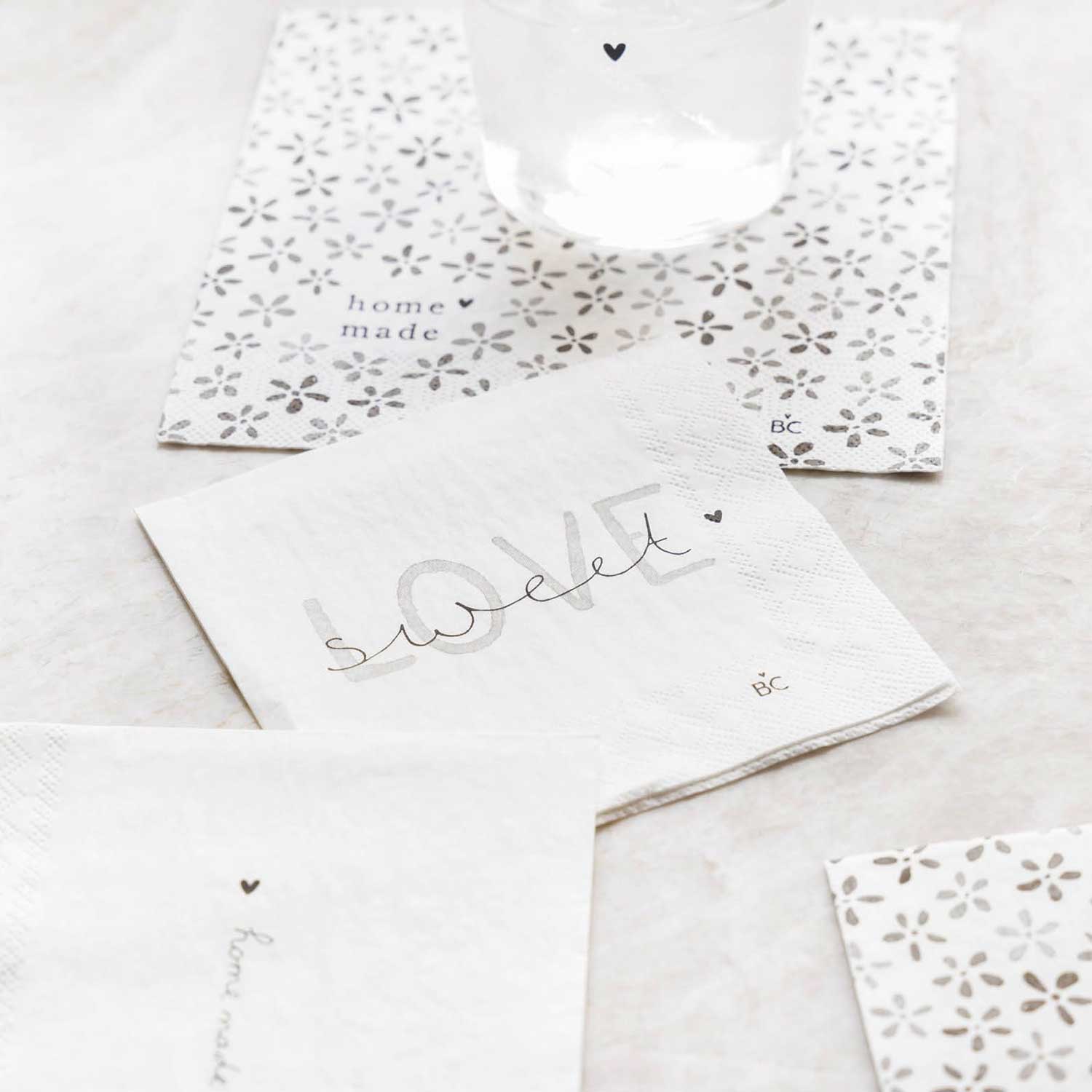 Weiße Papierserviette mit Sweet-Love-Schriftzug und kleinen Blüten-/Sternmustern, gefaltet
