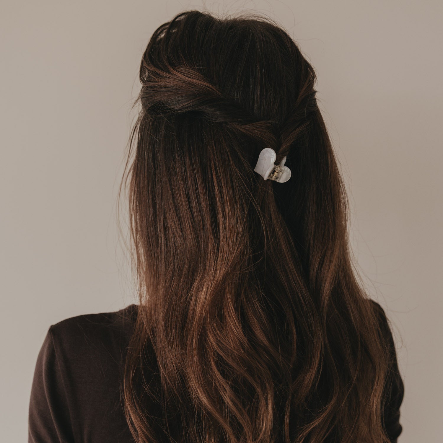 Kleine Haarspange in Herzform, perlmuttfarben, am Hinterkopf im Haar befestigt