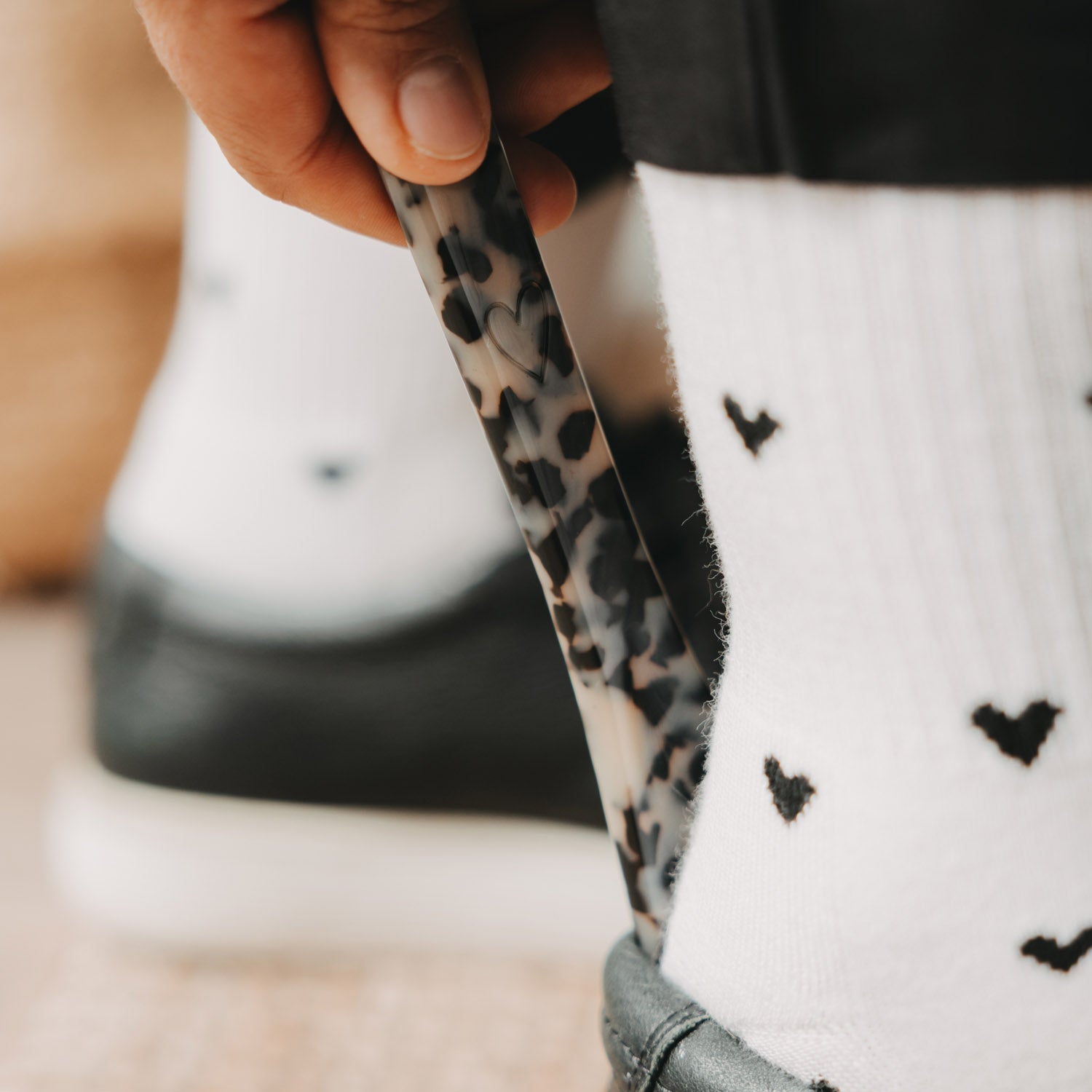 Schuhanzieher mit Leopardenmuster, Hand führt ihn an den Schuh an