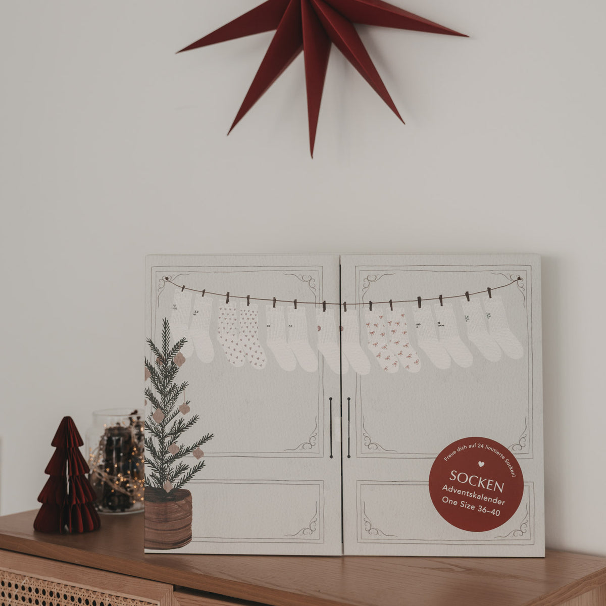 Socken-Adventskalender, geschlossene Klappbox mit Socken-Illustrationen und rundem Aufkleber