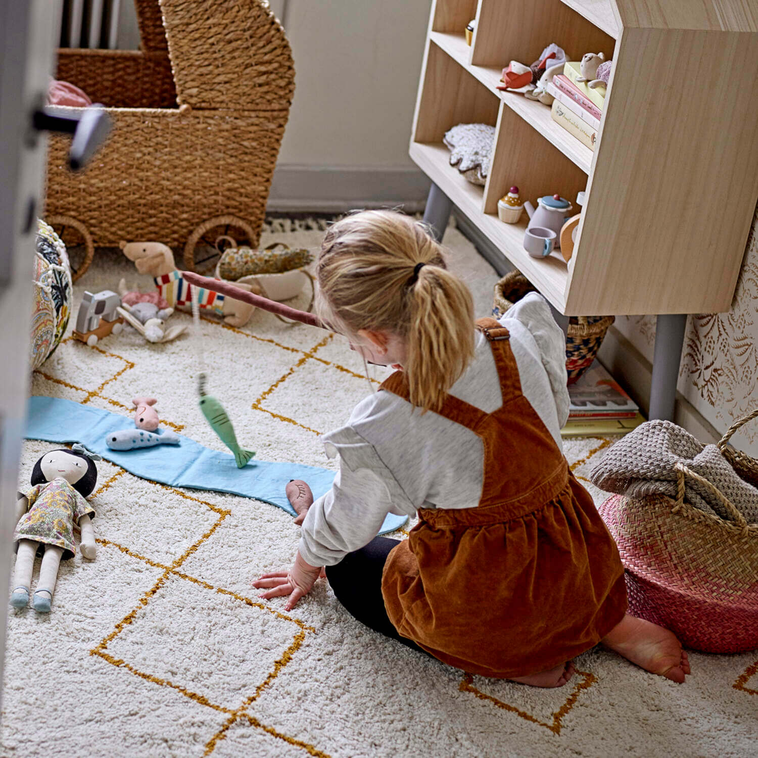 Kinder-Spieldecke mit hängenden Stofffischen, Kind kniet am Boden beim Spielen