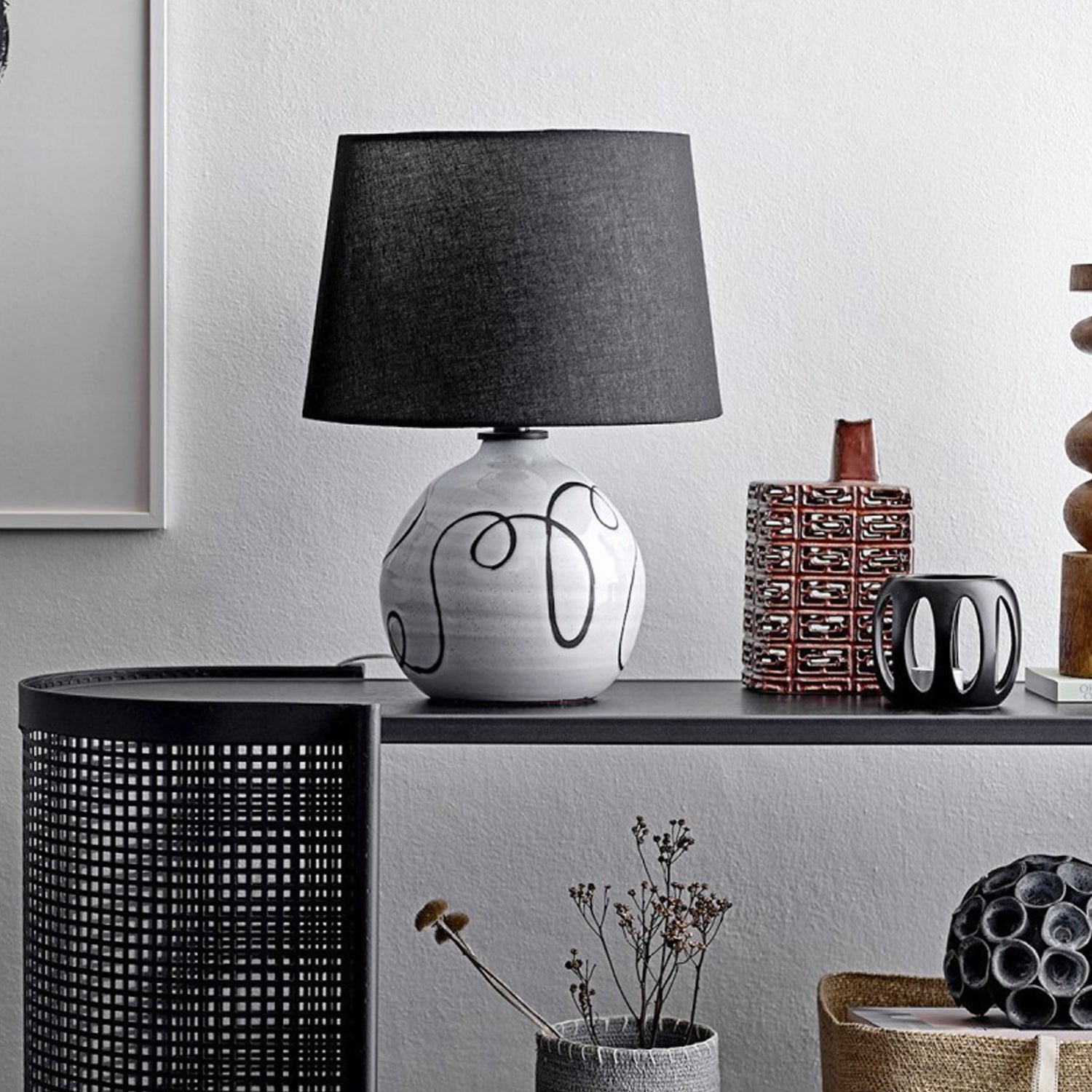 Tischlampe mit dunklem Stoffschirm und weißer Keramikbasis mit abstraktem Linienmuster