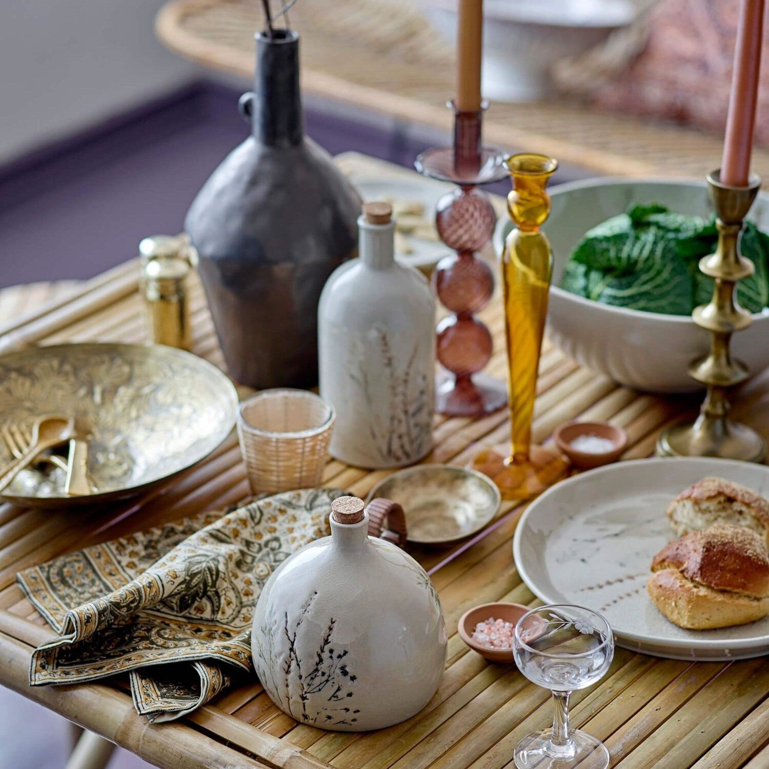 Goldfarbenes Tablett mit Deko-Flaschen und Glas auf Holztablett